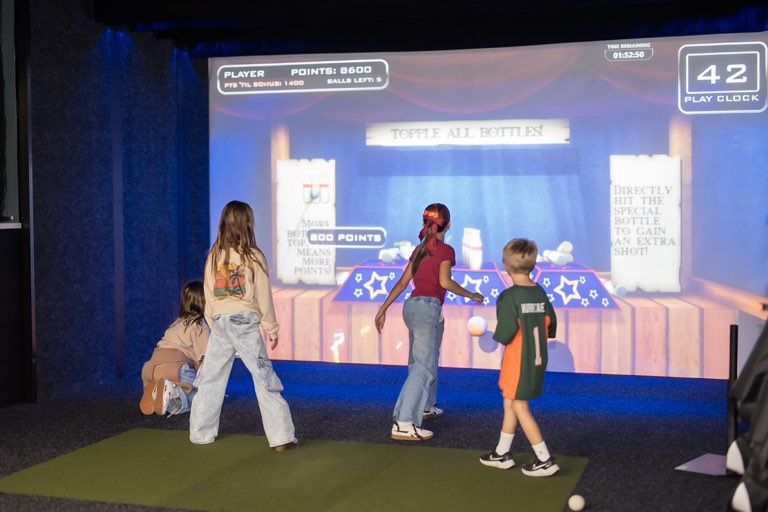 Kids throwing balls at a carnival bottle-toss game on the simulator screen