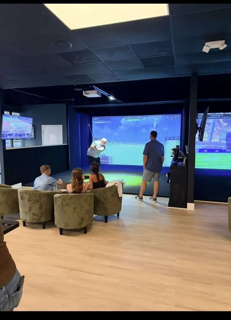 Family watching a golfer tee off at Golfer's Den