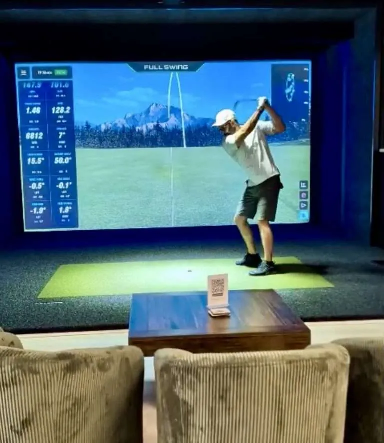 Golfer mid-swing with Full Swing shot data on screen